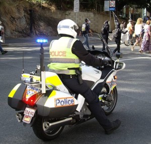 Left: A Queensland ‘bikie’ keeps close watch on the tail end of a protest march through the streets of Brisbane in November 2013.                       – Kristine Klugman photo